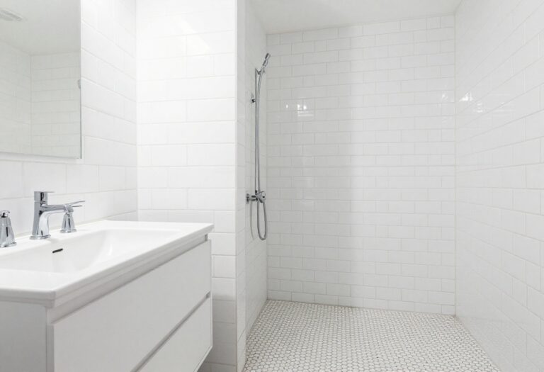 All-white bathroom with layered tile designs, natural lighting, and clean decor elements for a home decor blog.