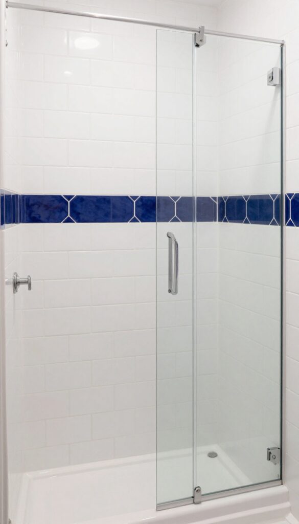 A classic shower with white subway tiles and a horizontal navy blue hexagon tile border accent at eye level in bright natural light.