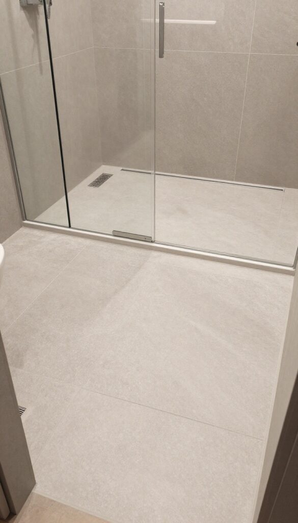 Double shower with textured floor tiles and linear drain
