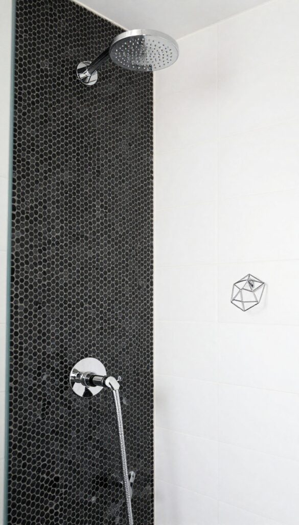 A modern bathroom shower with a geometric accent wall of black hexagon mosaic tiles on white grout, under bright natural light and minimalist fixtures.