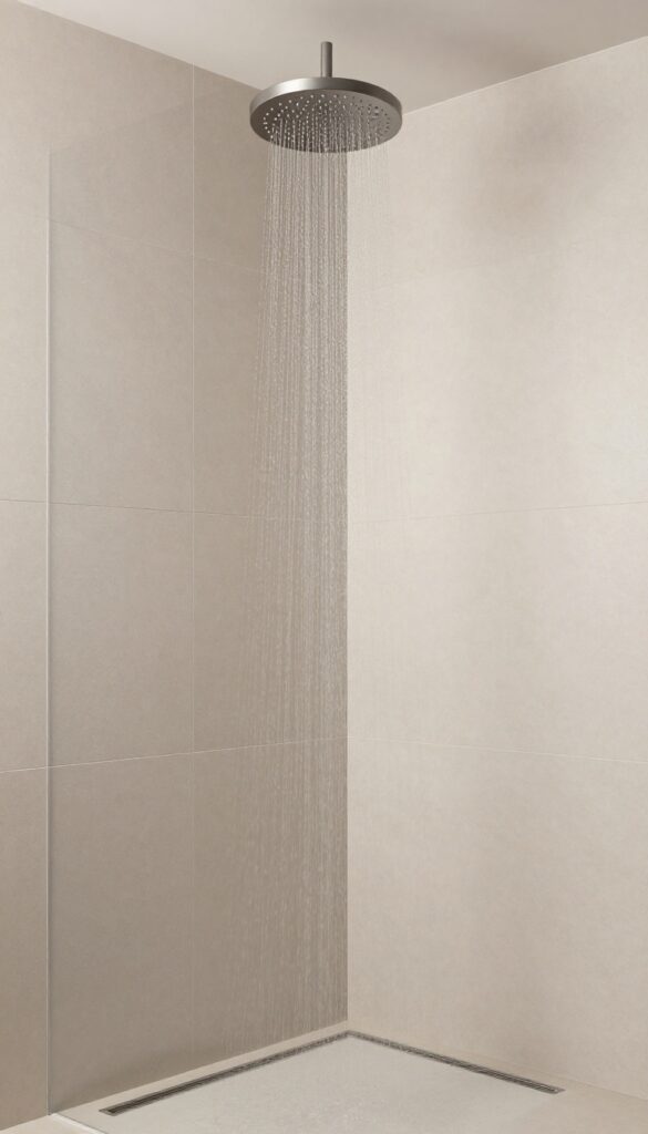 Neo-angle shower with centered rain shower head over corner, neutral tiles, bright natural light