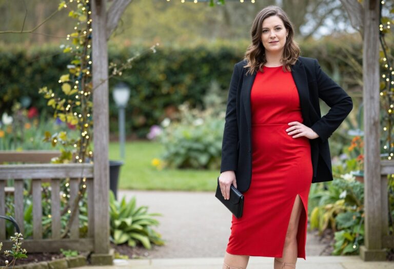 Woman in bold red midi dress with blazer at garden wedding