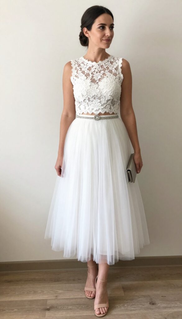 Adult woman with standard body type wearing a white lace crop top and high-waisted tulle skirt, standing in a ballroom with exposed brick walls and industrial lighting, natural light, warm romantic vibe.