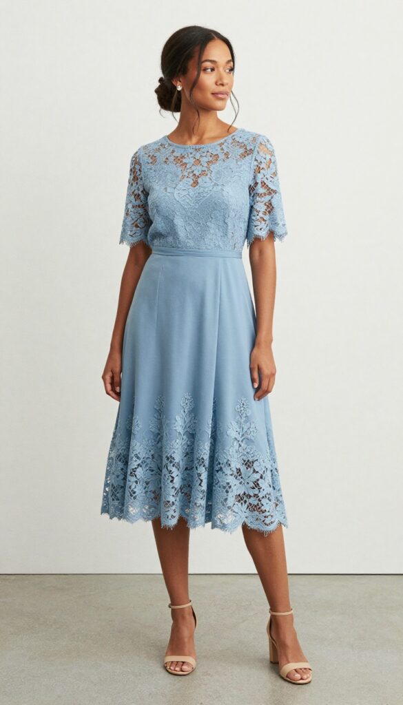 A woman in a dusty blue A-line wedding dress with lace sleeves standing in a sunlit garden with greenery and white flowers.