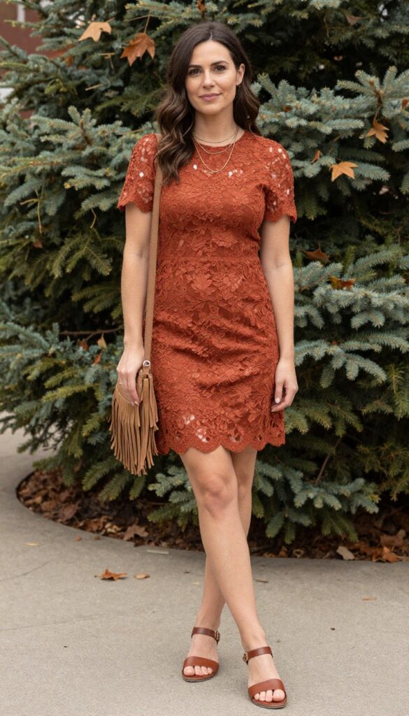 Woman in rust lace mini dress and brown leather sandals standing in autumn grass, smiling naturally