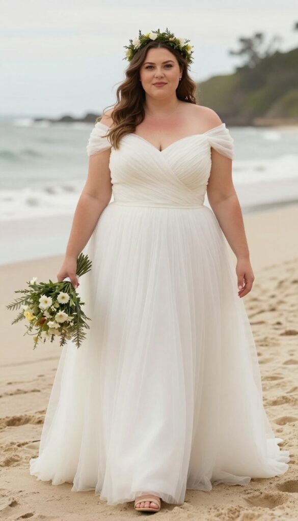 Plus size bride in off-the-shoulder tulle ball gown on beach at golden hour, floral crown, holding bouquet, joyful expression.
