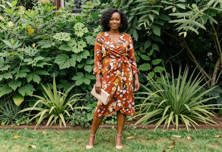 Black woman in floral wrap midi dress and nude block heels as wedding guest outfit