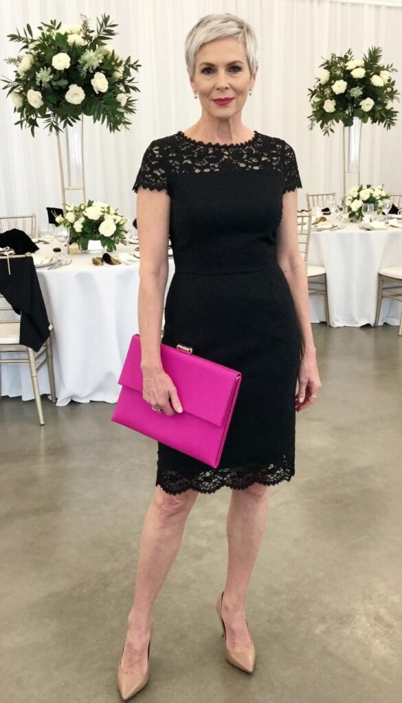 Petite woman over 50 in black lace dress with fuchsia clutch at wedding reception