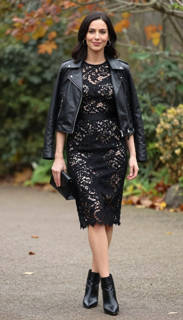 Goth wedding guest outfit: black lace sheath dress, fitted black leather jacket, silver hoop earrings, black ankle boots, black clutch, in autumn garden.