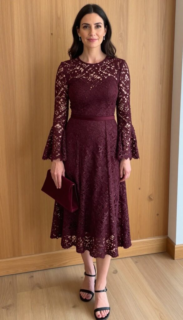 A woman with fair skin and dark hair wearing a deep wine high-neck lace dress with bell sleeves, standing in a warmly lit room with wood tones, holding a small burgundy clutch, wearing strappy black sandals.