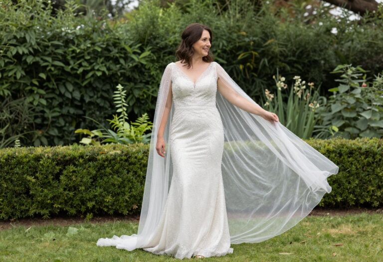 Woman in crystal wedding dress with sheer cape in garden