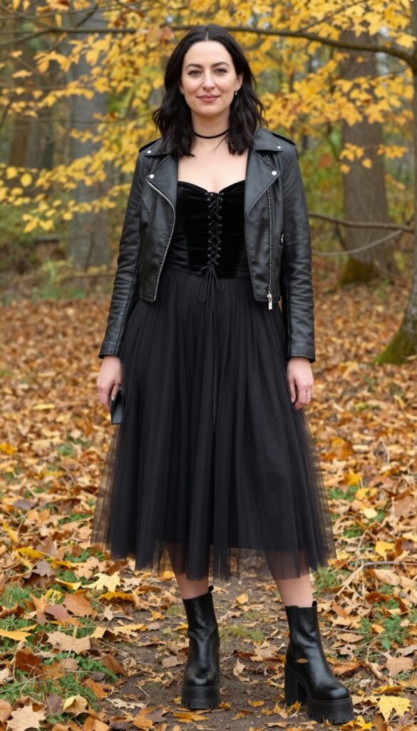 Woman in black velvet corset and charcoal tulle skirt with platform boots and leather jacket in autumn forest