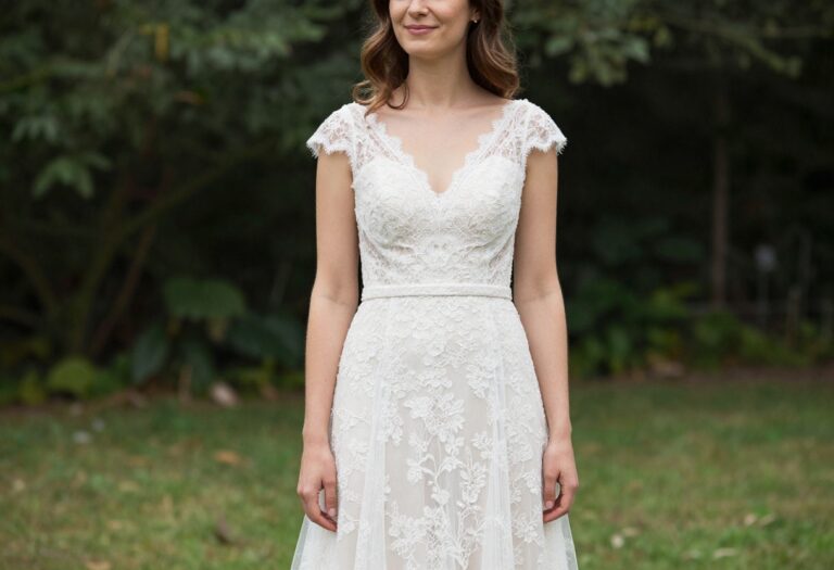 Woman in lace A-line wedding dress with illusion sleeves standing in garden