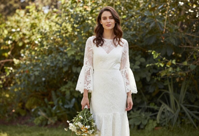 Woman in flowy sleeves wedding dress with boho train in garden