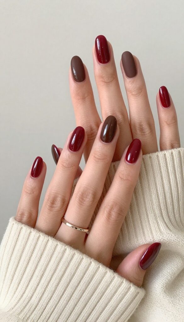 Chocolate cherry dip powder nails with glossy cherry red and matte chocolate brown on almond-shaped nails