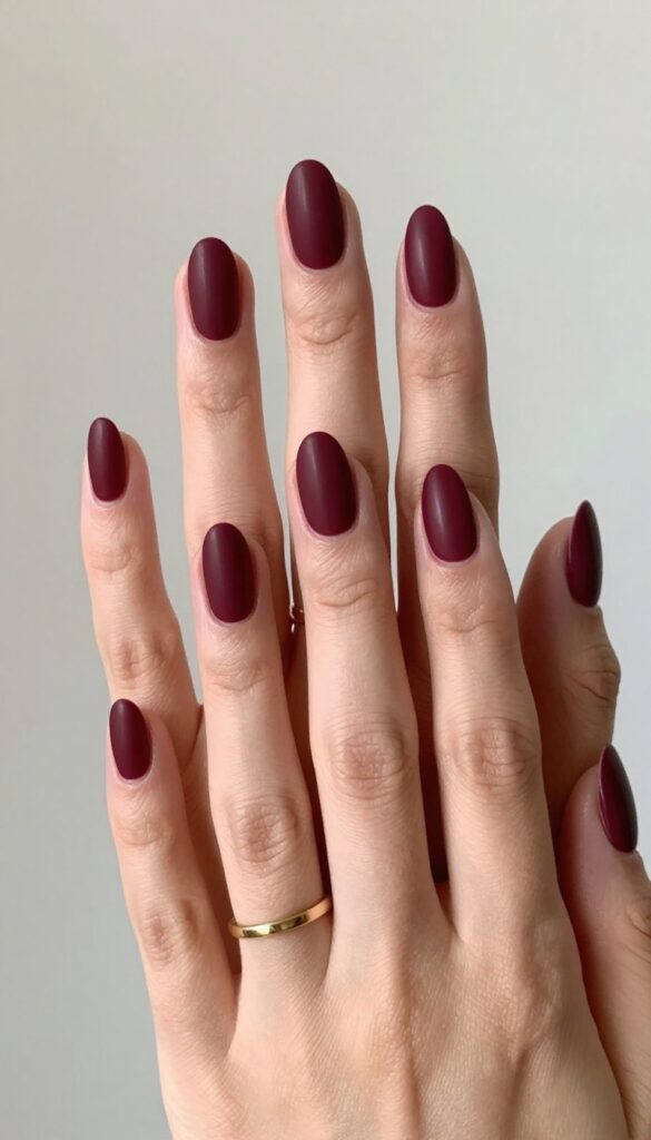 Matte burgundy almond nails with gold ring