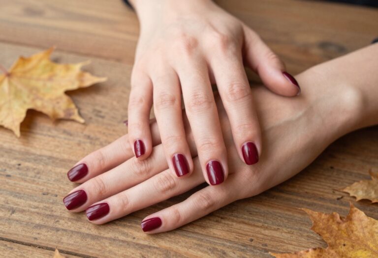 Short square nails in glossy burgundy with autumn leaves