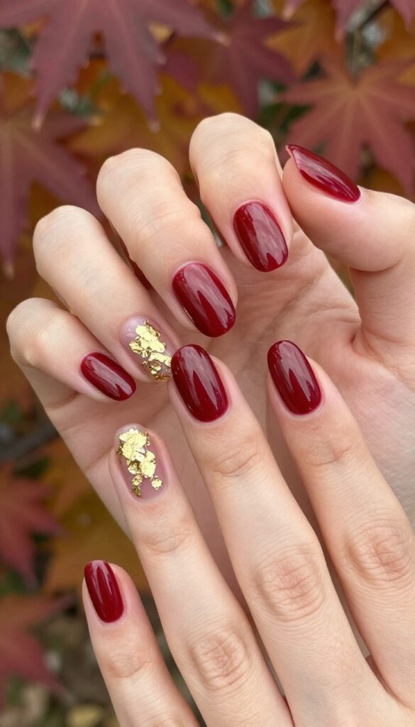 Cranberry chrome nails with gold foil accents on almond-shaped nails