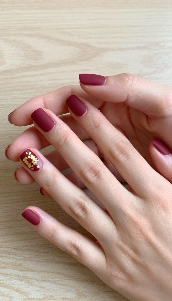 Short square nails in matte burgundy with gold foil accents