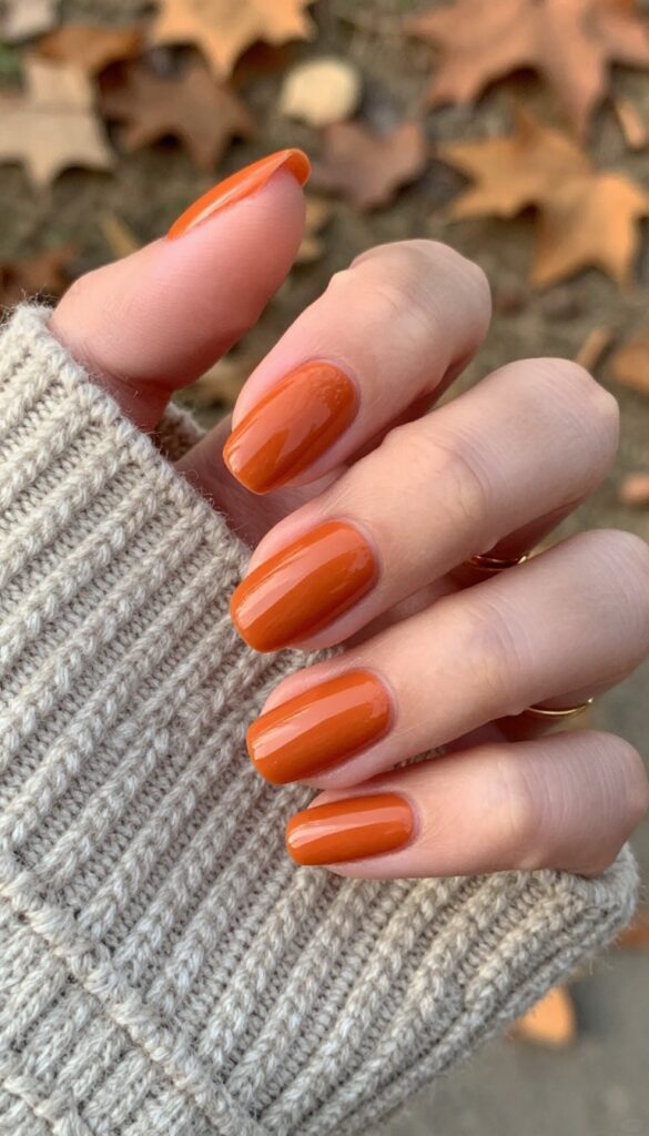 Glossy burnt orange gel nails on almond-shaped nails, fall manicure idea