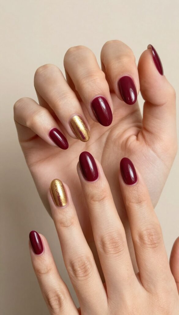 Burgundy cat eye nails with metallic gold stripe on almond-shaped nails