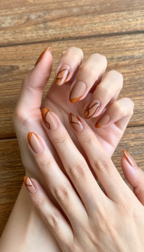 Cinnamon swirl almond nails with burnt orange and brown swirls on a nude base, matte finish, autumn manicure