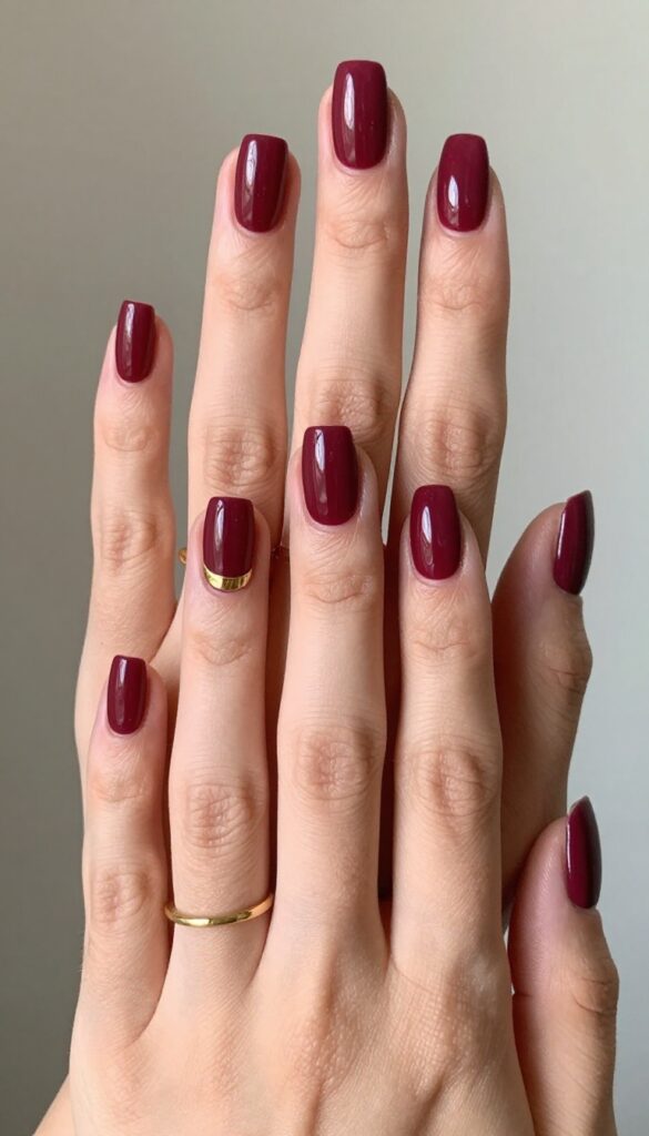 Velvet burgundy matte nails with gold leaf accent on ring finger
