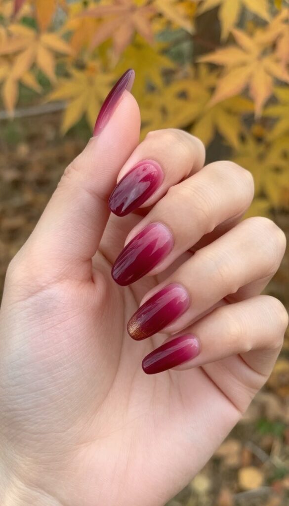 Cranberry ombré acrylic nails with gold shimmer on almond shape