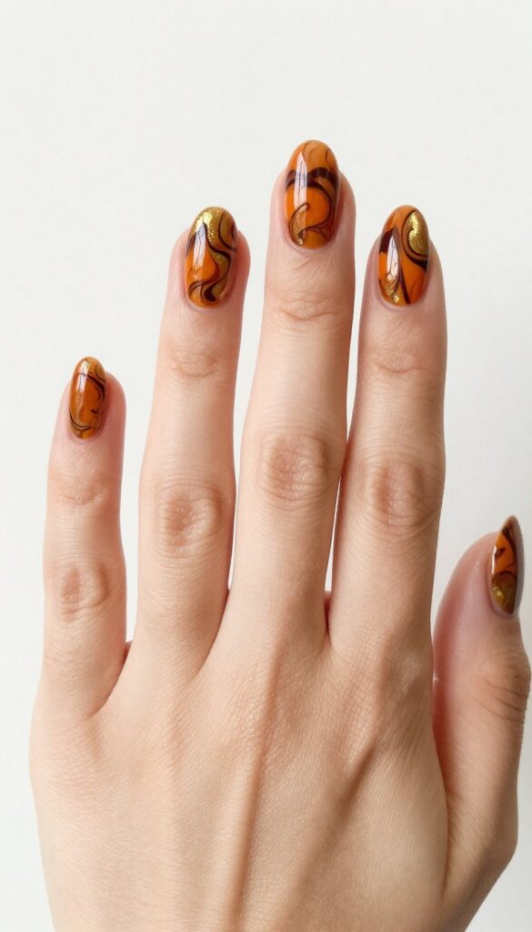 Pumpkin spice marble nails with burnt orange, brown, and gold swirls on almond-shaped nails