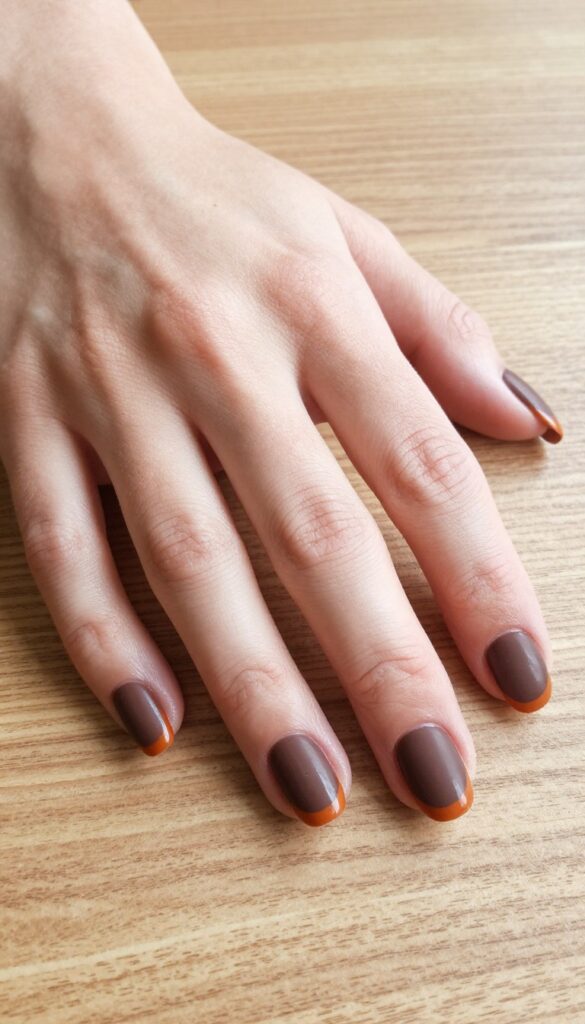 Matte brown nails with glossy orange tips fall manicure