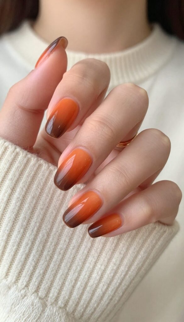 Burnt orange ombré nails with brown tips on almond-shaped nails