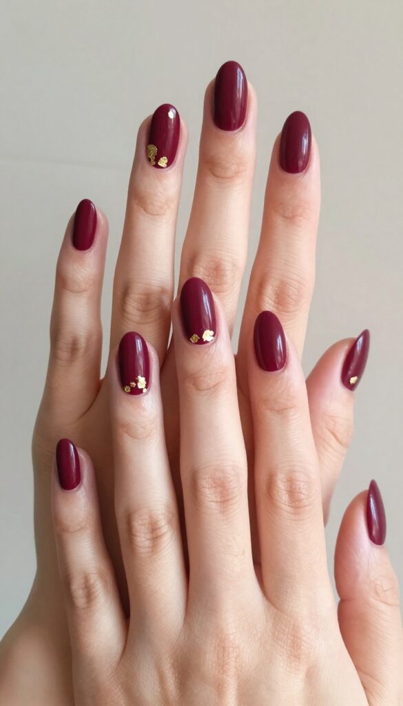 Velvet burgundy almond nails with gold foil accents for fall wedding