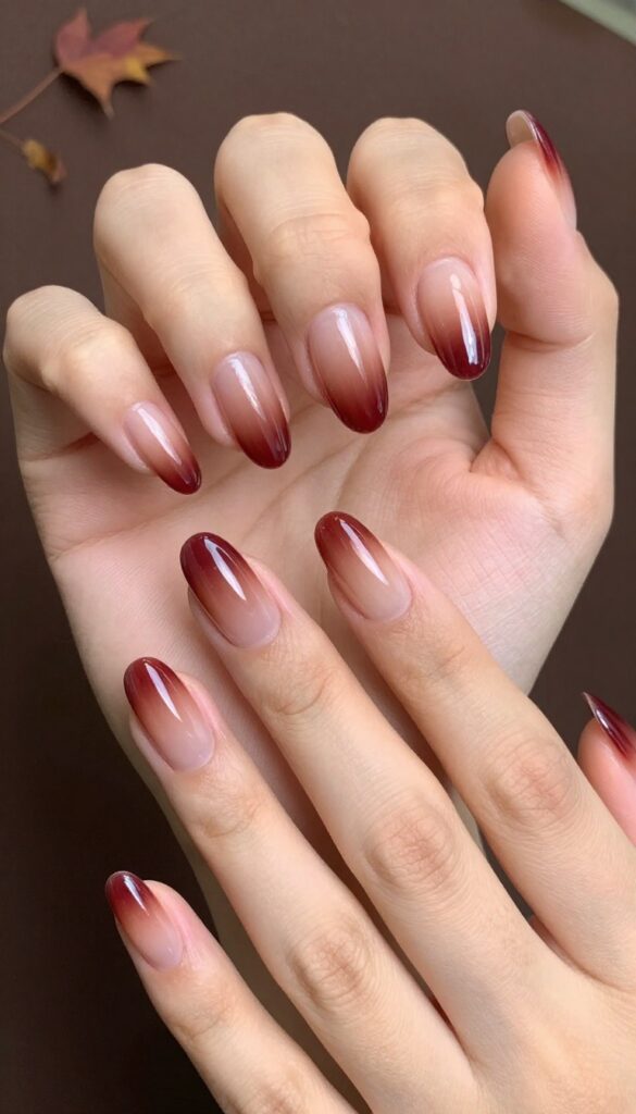 Cranberry chrome ombré acrylic nails on almond shape, fading from nude to deep cranberry with glossy chrome finish