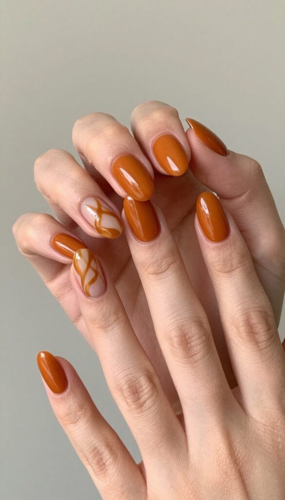 Caramel swirl pumpkin nails with glossy burnt orange base and amber swirls on accent nails