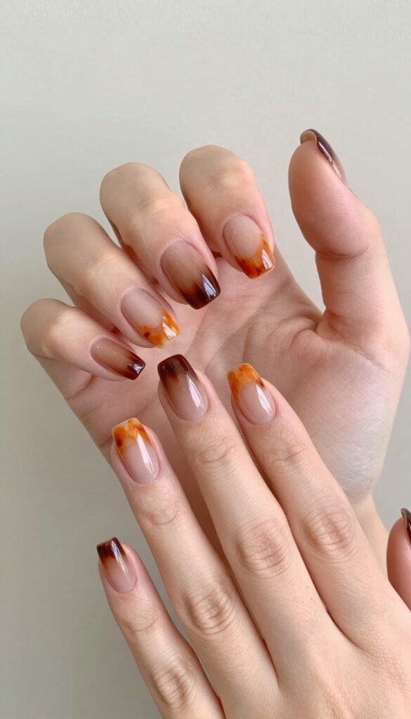 Tortoiseshell French tip nails with burnt orange, amber, and brown patches on a nude base