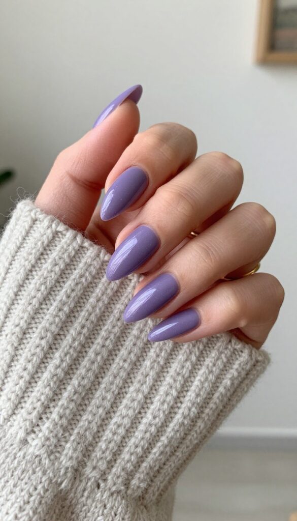 Smoky amethyst stiletto nails with shimmer finish on a hand resting on a cozy knit sweater