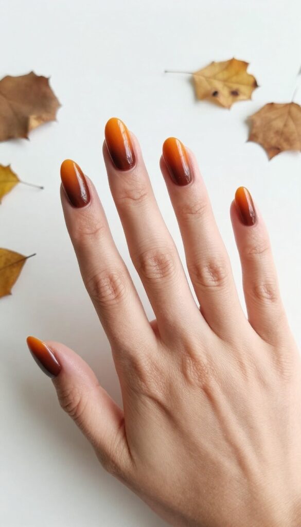 Ombre gradient nails from burnt orange to cocoa brown on almond-shaped nails
