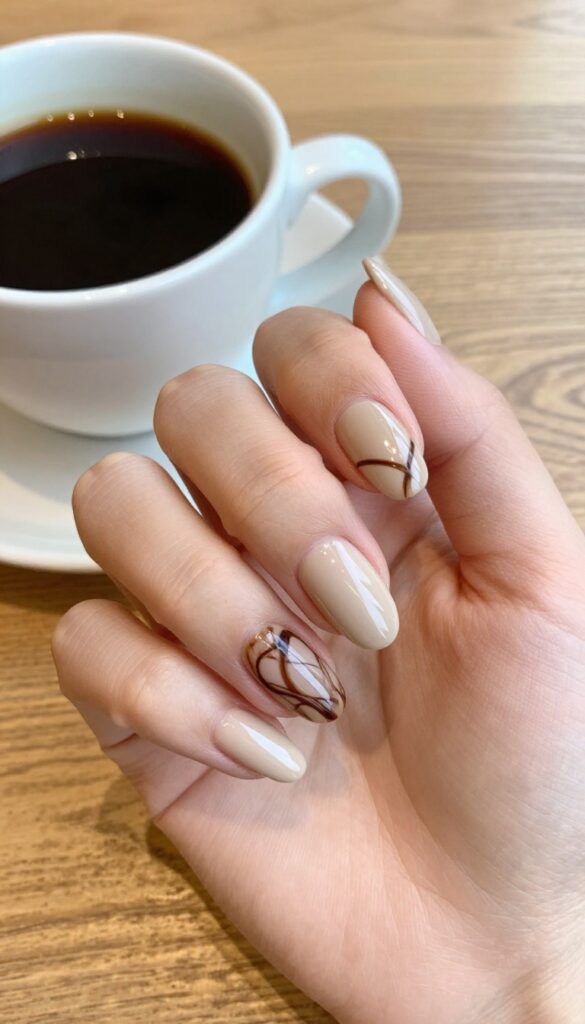 Almond nails with chocolate mocha swirl design, glossy finish, resting near a coffee cup