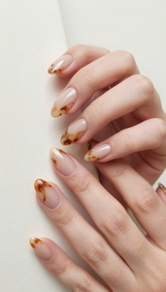 Tortoiseshell swirl accent nails with warm brown and amber marbled design on almond-shaped nails