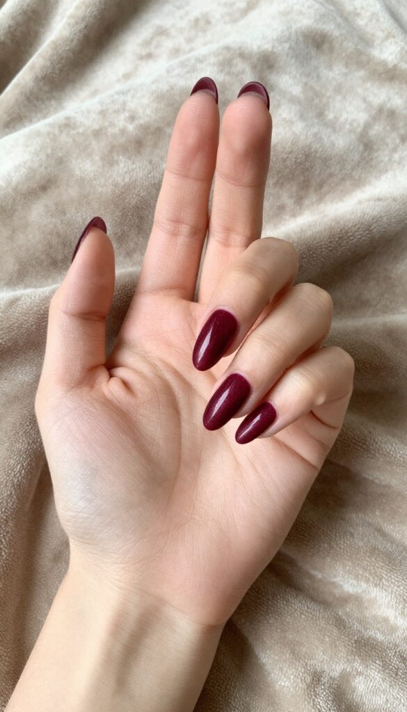Burgundy velvet nails with plush shimmer finish on almond-shaped nails