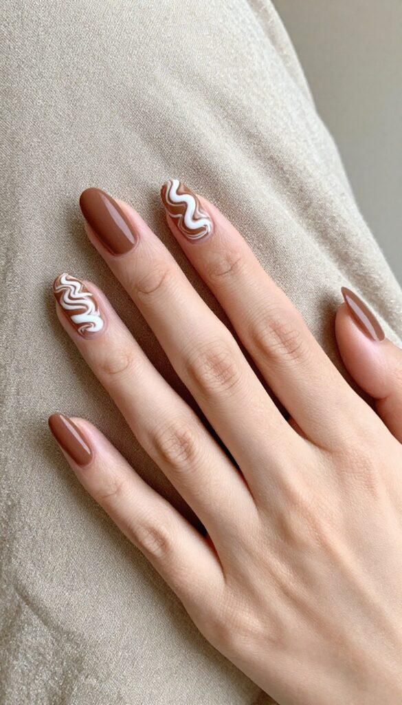 Short almond nails with mocha swirl design in warm brown and white, matte finish, fall manicure