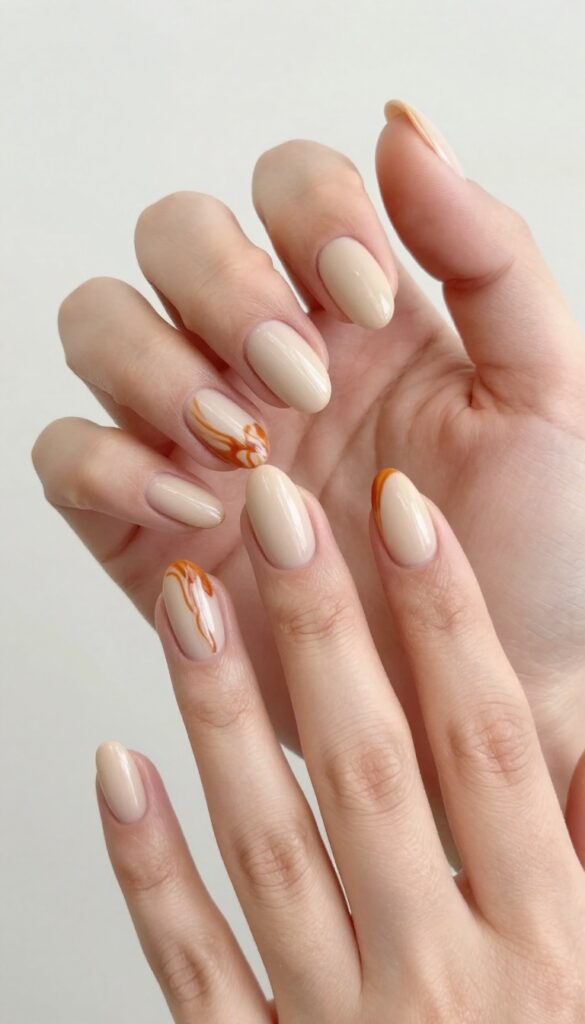 Burnt orange swirls on nude almond nails with matte finish