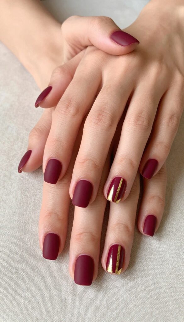 Short matte merlot nails with delicate gold foil accents, elegant fall manicure