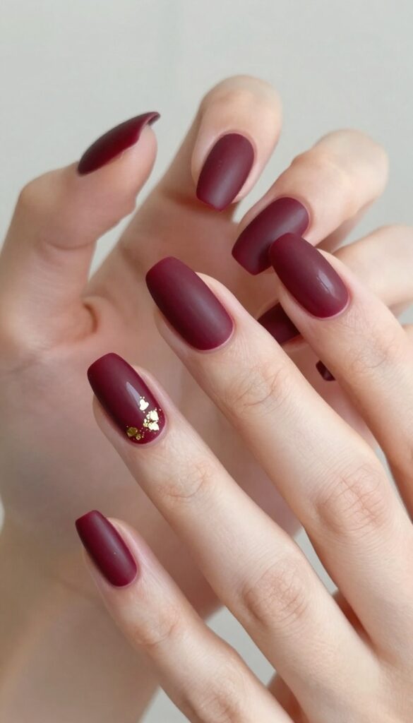 Matte merlot nails with gold foil accent on ring finger