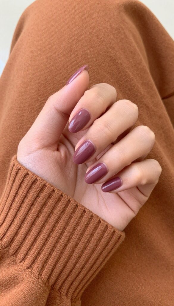 Smoky plum almond nails with glossy finish on a woman's hand