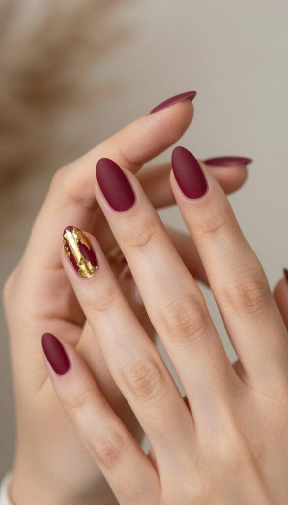 Matte merlot nails with gold foil accent on ring finger