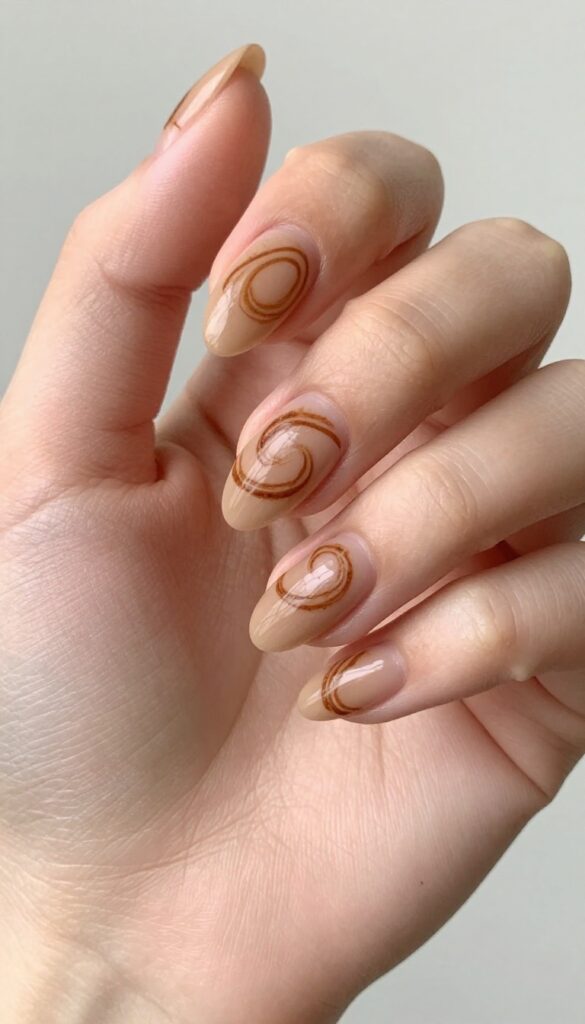 Almond nails with rustic cinnamon swirl design on nude base, matte finish