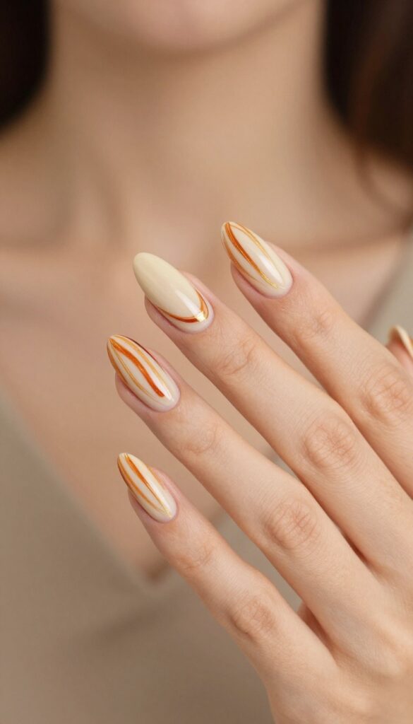Pumpkin spice swirl nails with nude base and burnt orange, cinnamon, and gold swirls on almond-shaped nails.