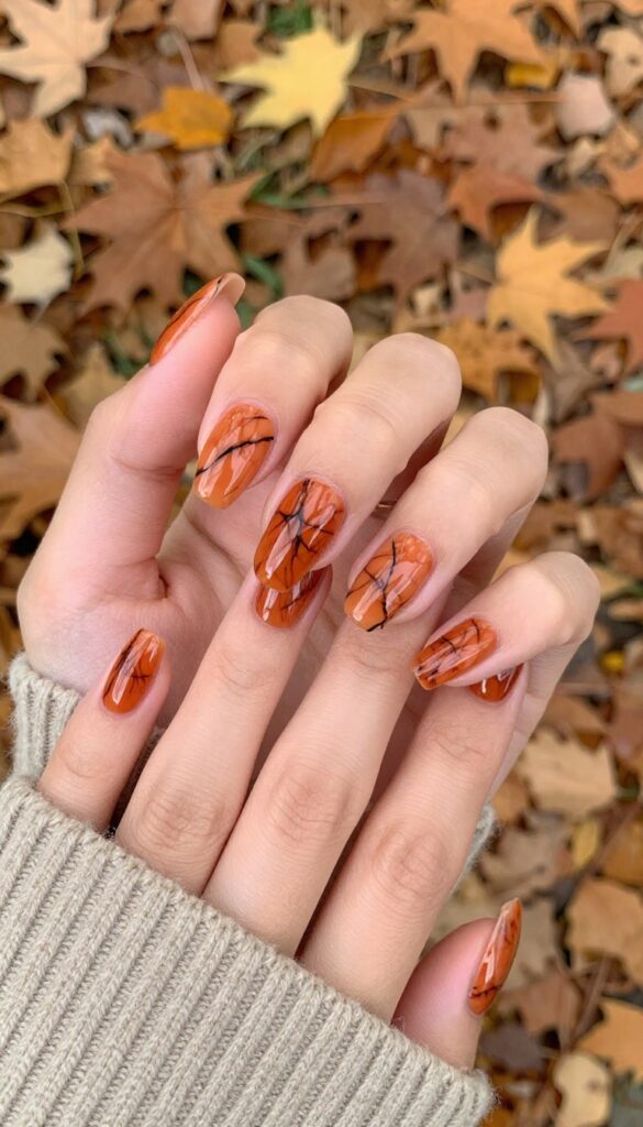 Burnt orange marble swirl acrylic nails on almond-shaped nails with glossy finish