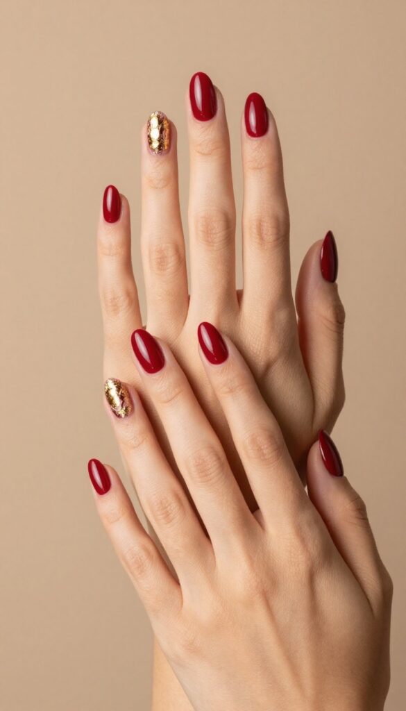 Cranberry red nails with gold foil accents on short almond shape